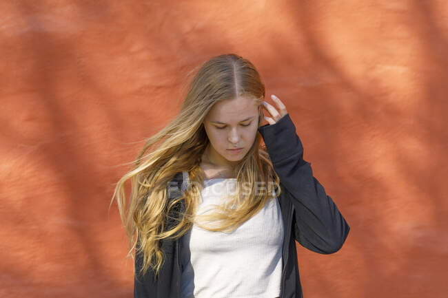 Blonde junge Frau an orangefarbener Wand — Stockfoto