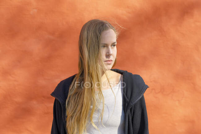 Loira cabelo jovem mulher por laranja parede — Fotografia de Stock