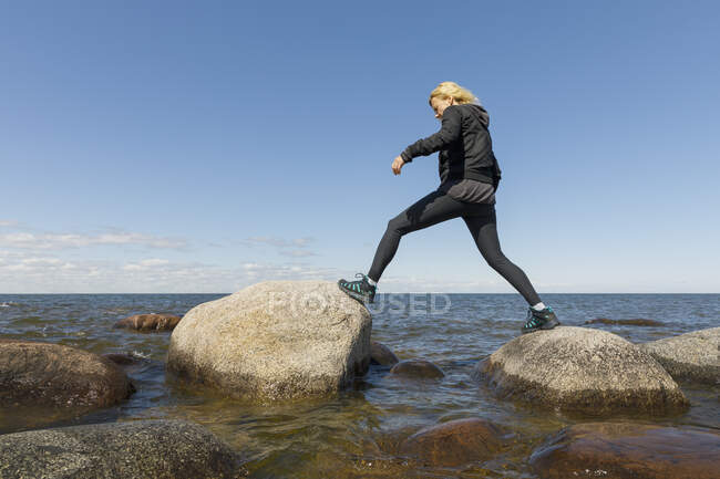 Femme marchant sur des rochers dans le lac Vanern, Suède — Photo de stock