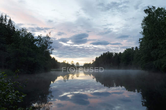 Nuvens refletidas no lago ao pôr do sol — Fotografia de Stock