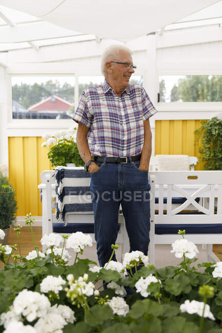 Sorrindo homem sênior por flores brancas — Fotografia de Stock
