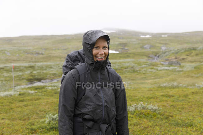 Smiling woman in hooded jacket during hike — Stock Photo