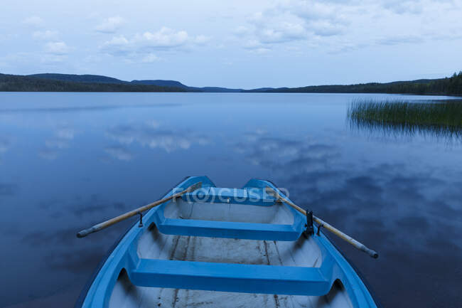 Row boat on reflective lake — Stockfoto