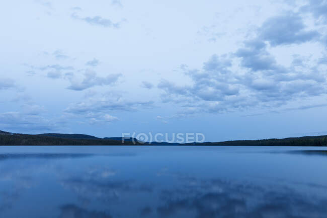 Nubes sobre el lago azul reflectante - foto de stock