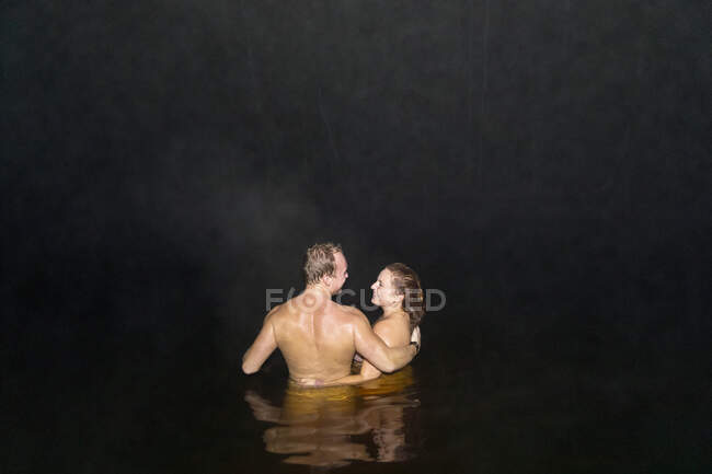 Sorridente coppia nuoto nudo di notte — Foto stock