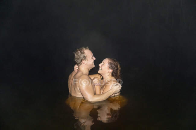 Sonriente pareja nadando desnuda por la noche - foto de stock