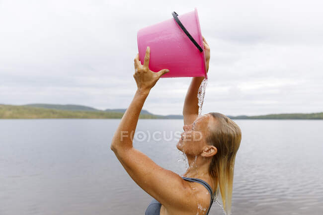 Женщина купается с ведром воды из озера — стоковое фото