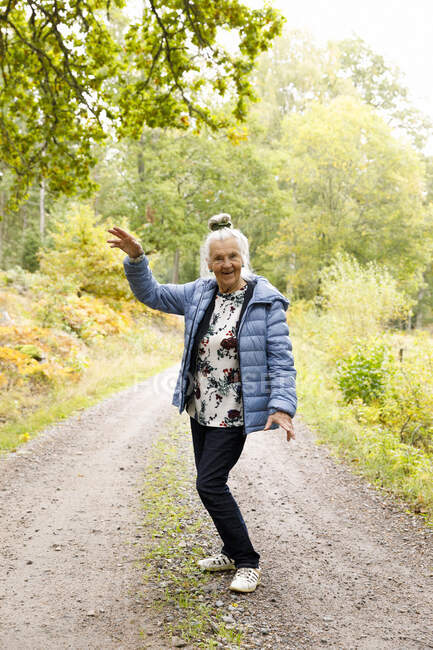 Sorridente donna anziana sulla strada rurale — Foto stock