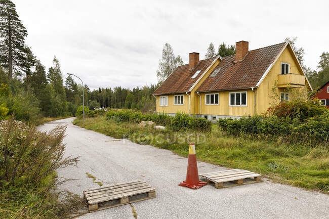 Casa por estrada rural bloqueada com cone de trânsito e paletes de madeira — Fotografia de Stock