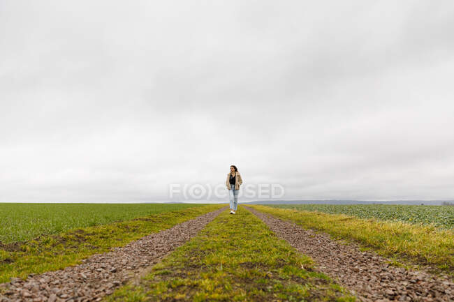 Молода жінка йде сільською дорогою. — стокове фото