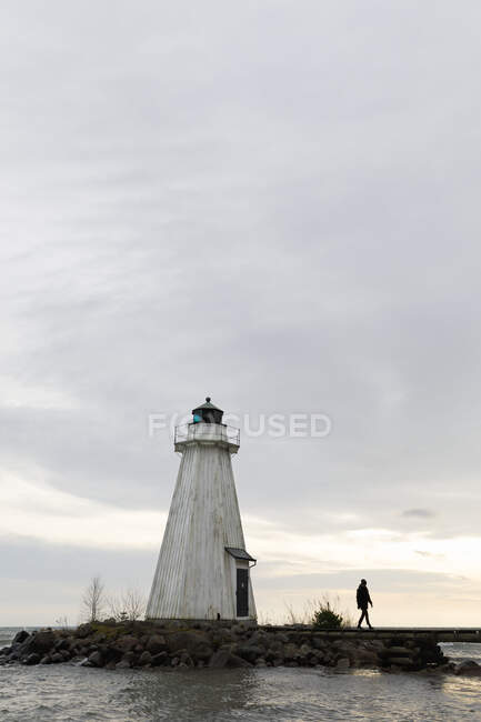 Woman walking by lighthouse at Lake Vattern, Sweden — Stockfoto