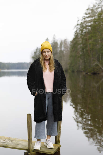 Jeune femme en bonnet jaune au bord du lac — Photo de stock