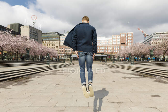 Young man jumping in public square — Stock Photo