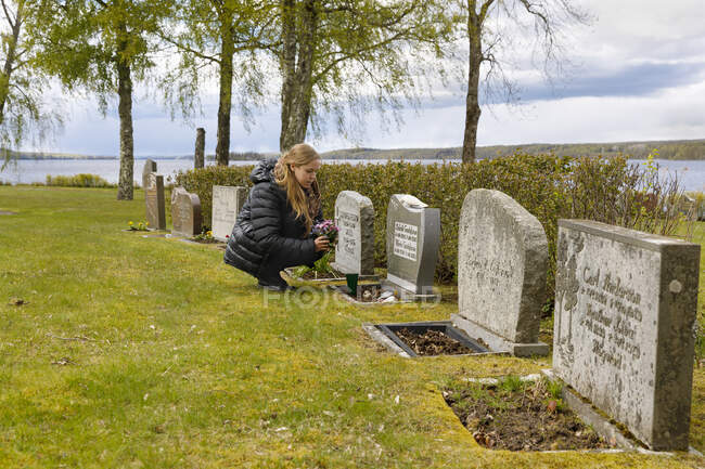 Young woman leaving flowers at grave — Foto stock