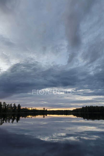 Lake under clouds at sunset — Stock Photo