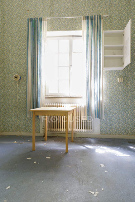 Table by window in abandoned mental hospital — Stock Photo