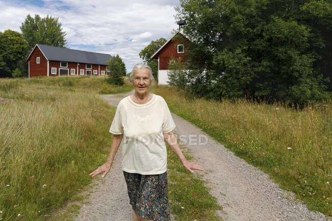 Senior woman walking on rural road - foto de stock
