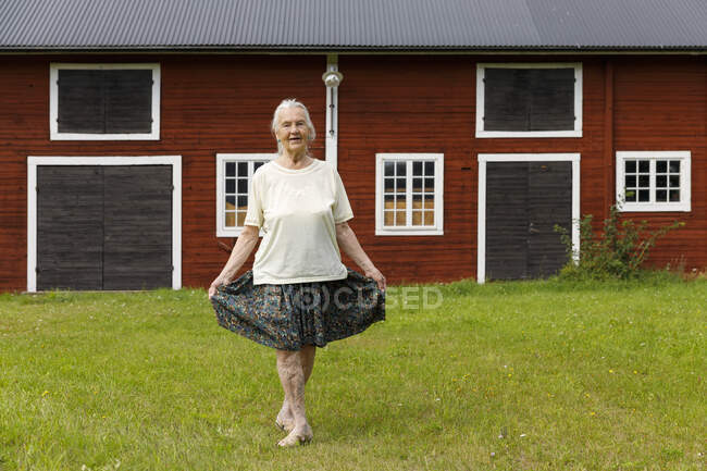 Senior woman doing curtsy by house — Stock Photo