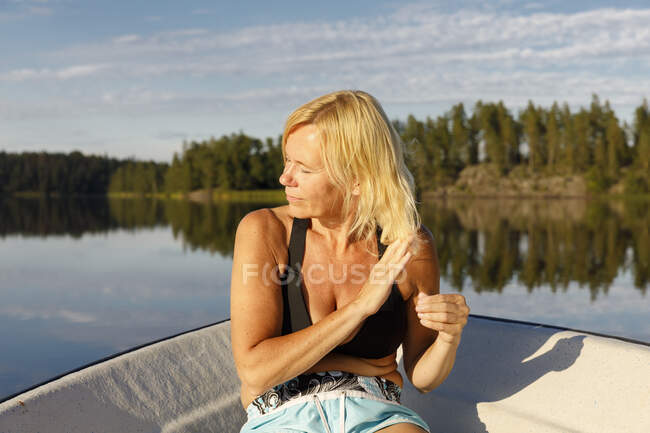 Зрелая женщина, сидящая в лодке на озере — стоковое фото