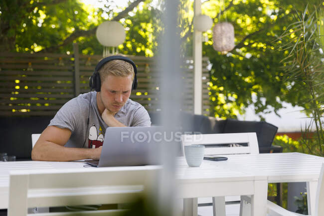 Young man working on laptop at outdoor table — Stock Photo