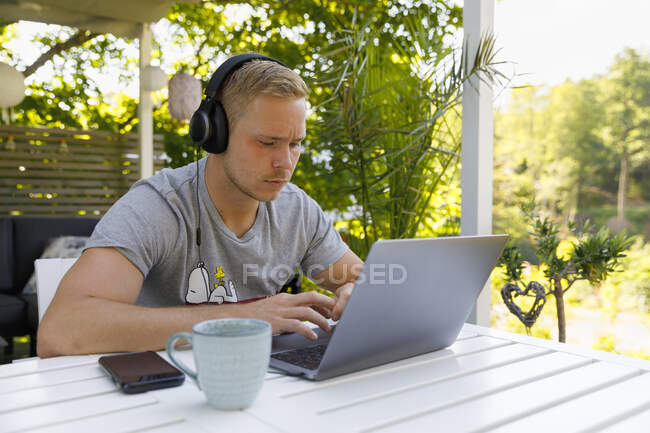 Young man working on laptop at outdoor table — Stock Photo