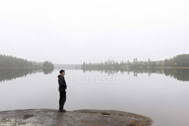 Man standing by Stora Skiren Lake, Sweden - foto de stock