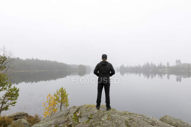 Man standing by Stora Skiren Lake, Sweden - foto de stock