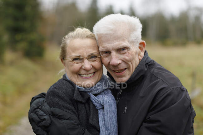 Smiling senior couple embracing in field — Foto stock