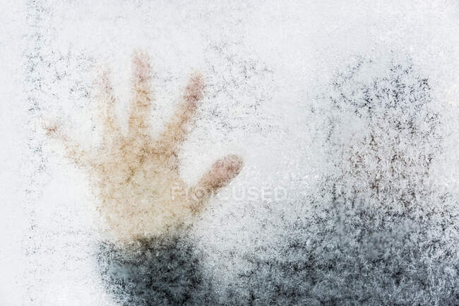 Woman's hand touching frosty window — Stock Photo
