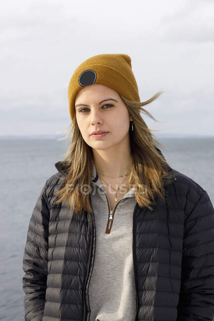 Young woman wearing warm clothing by sea — Foto stock