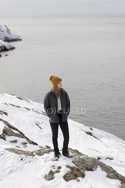Young woman standing on snow by sea — Foto stock