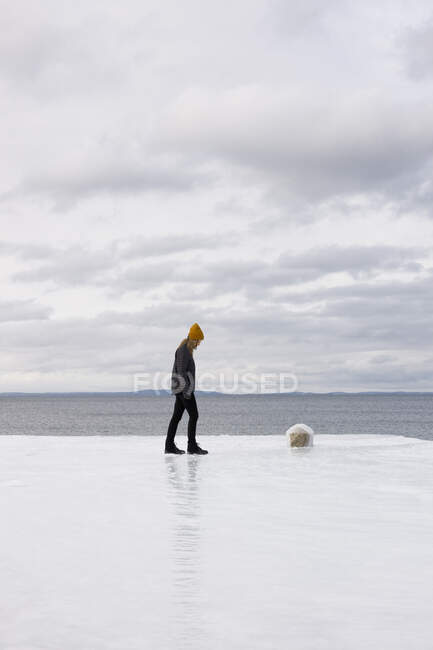 Young woman walking snowy pier by sea — Foto stock