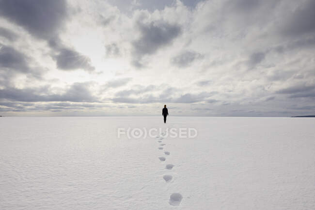 Pegadas atrás da mulher andando na neve — Fotografia de Stock