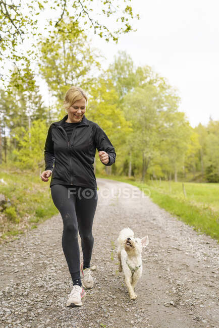 Frau joggt mit Hund — Stockfoto
