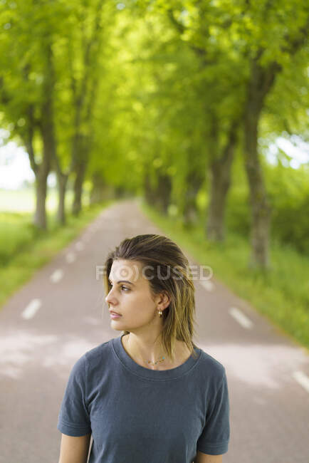 Молода жінка, що йде дорогою по деревах. — стокове фото
