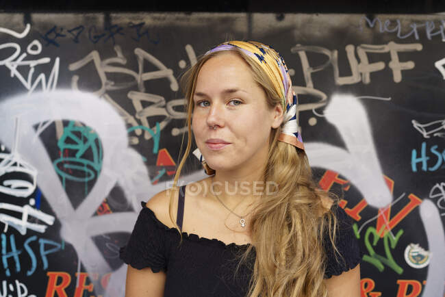 Junge Frau an Mauer mit Graffiti beworfen — Stockfoto