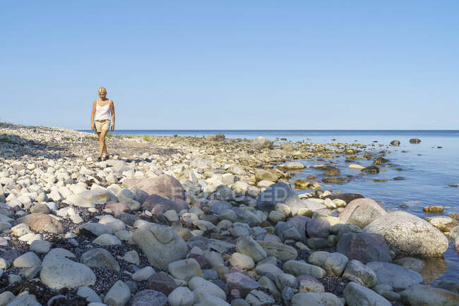 Woman walking on stone beach — Foto stock