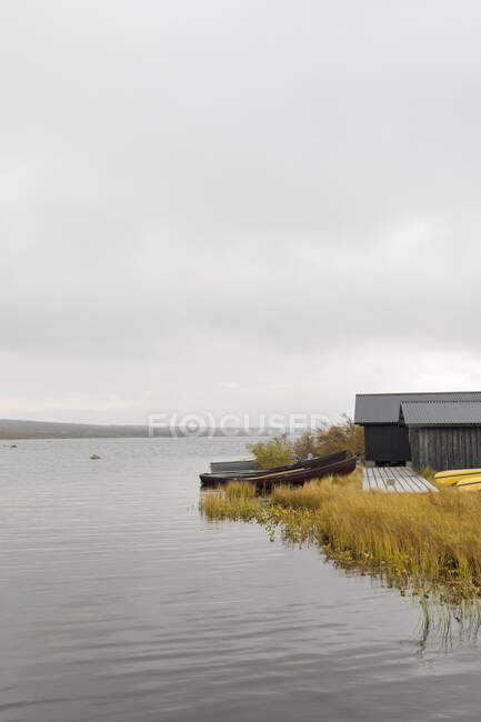 Boathouse on lake under clouds - foto de stock