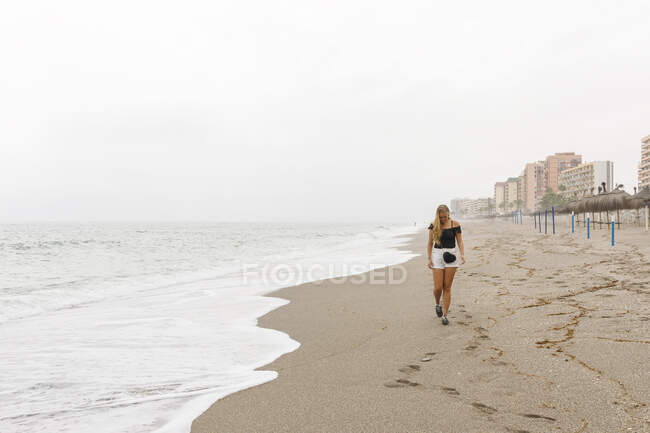 Giovane donna che cammina sulla spiaggia — Foto stock