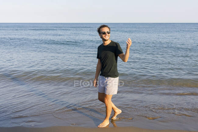 Lächelnder Mann mit Sonnenbrille am Strand — Stockfoto