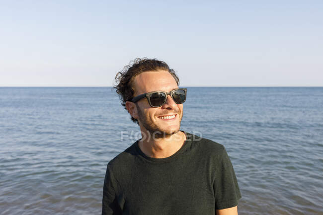 Усміхнений чоловік з сонцезахисними окулярами на пляжі — стокове фото