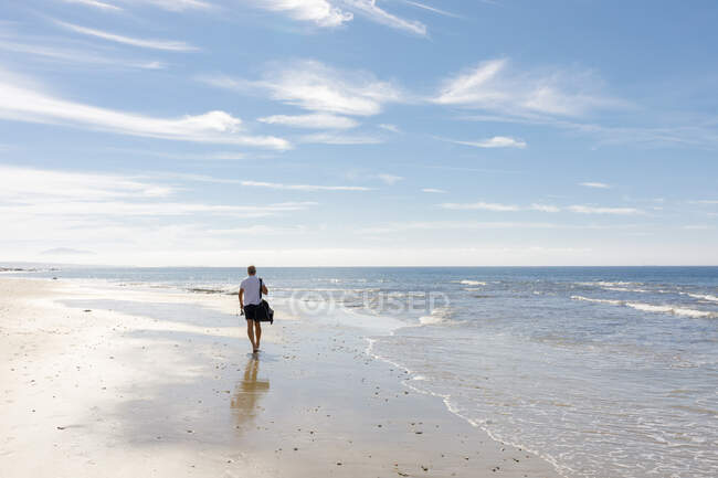 Человек гуляющий по пляжу — стоковое фото