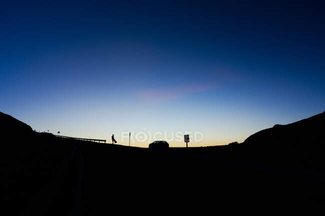 Donna e macchina in collina al tramonto — Foto stock
