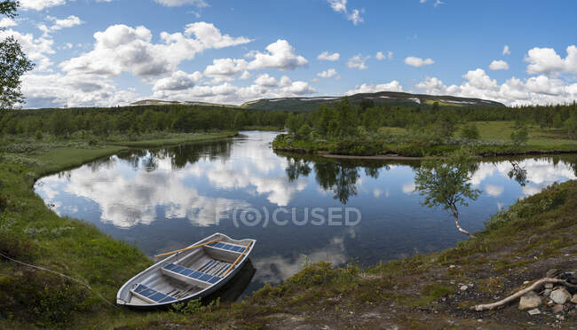 Boat and pond under clouds - foto de stock