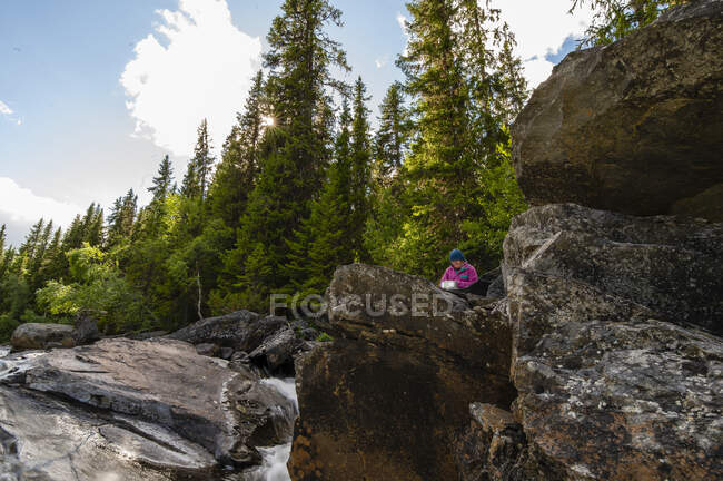 Woman hiking on rocks by river — Fotografia de Stock