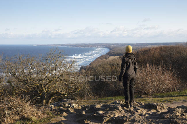 Young woman on hill by coast — Stockfoto