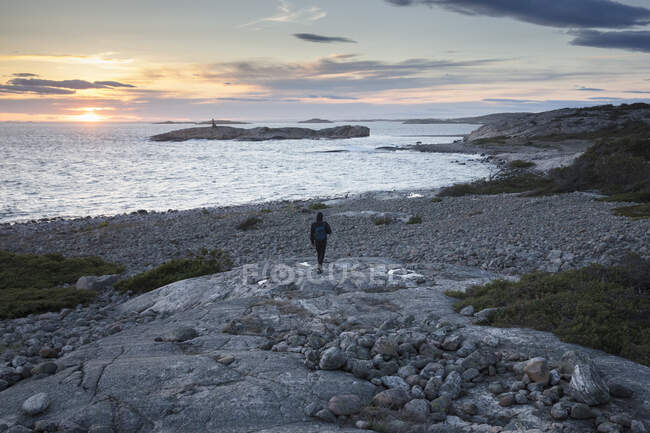 Homme randonnée par la mer au coucher du soleil — Photo de stock