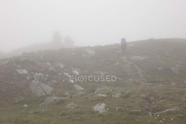 Junge Frau wandert im Nebel auf Hügel — Stockfoto