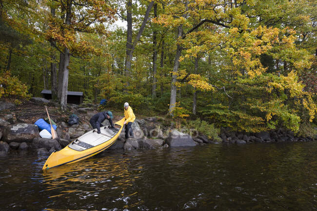 Hombres sosteniendo kayak de pie junto al río - foto de stock