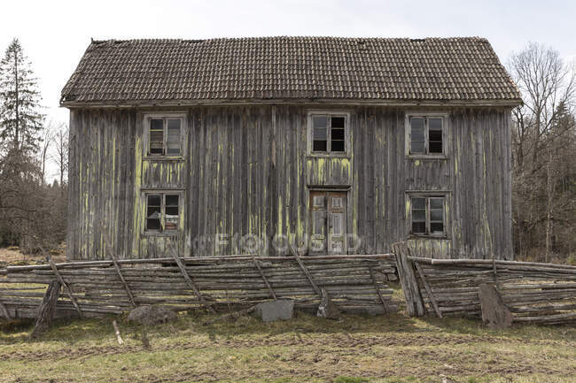 Abandoned house behind fence in field — Stock Photo